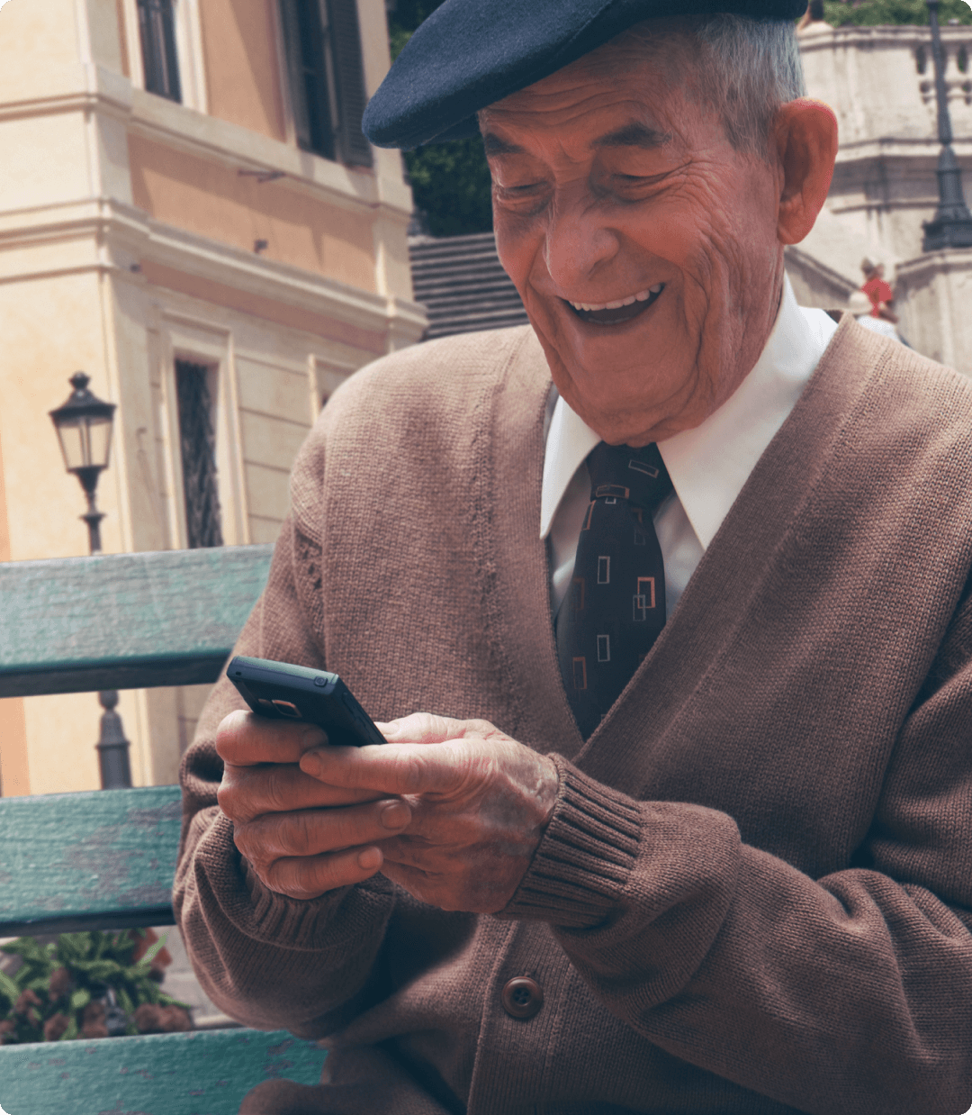 Un adulto mayor revisa su app bancaria desde su celular mientras disfruta un momento en una banca.