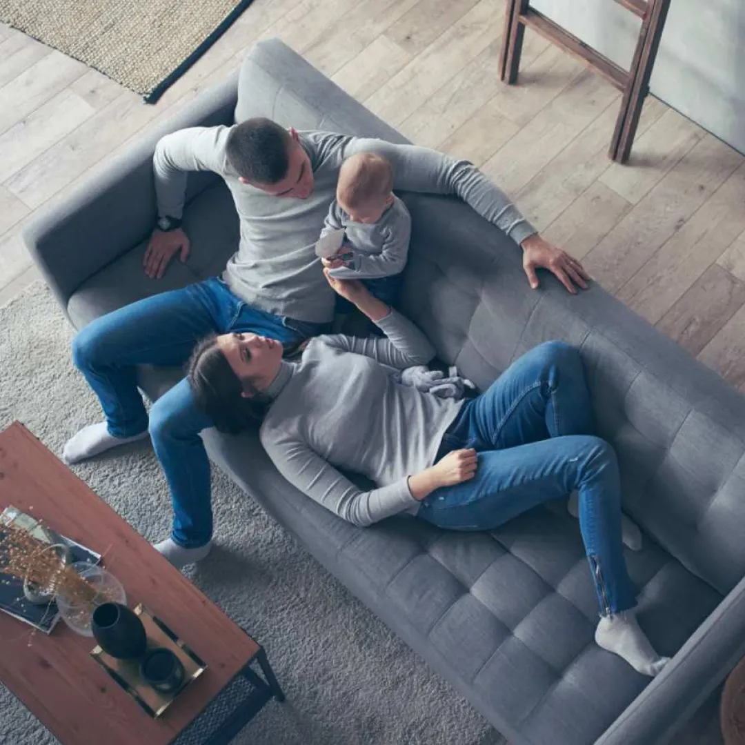 Familia descansando en la sala de su hogar, compartiendo tiempo juntos en un espacio cómodo y acondicionado para la vida familiar.