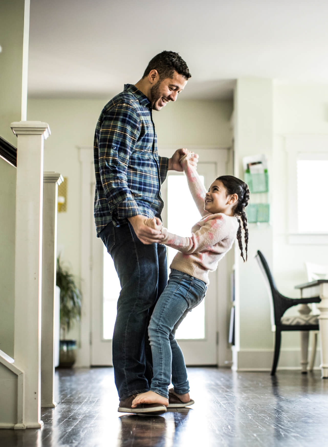 Papá bailando con su hija en la sala de su casa nueva, disfrutando un momento alegre.