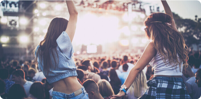 Un par de amigas disfrutando un concierto con los brazos arriba.