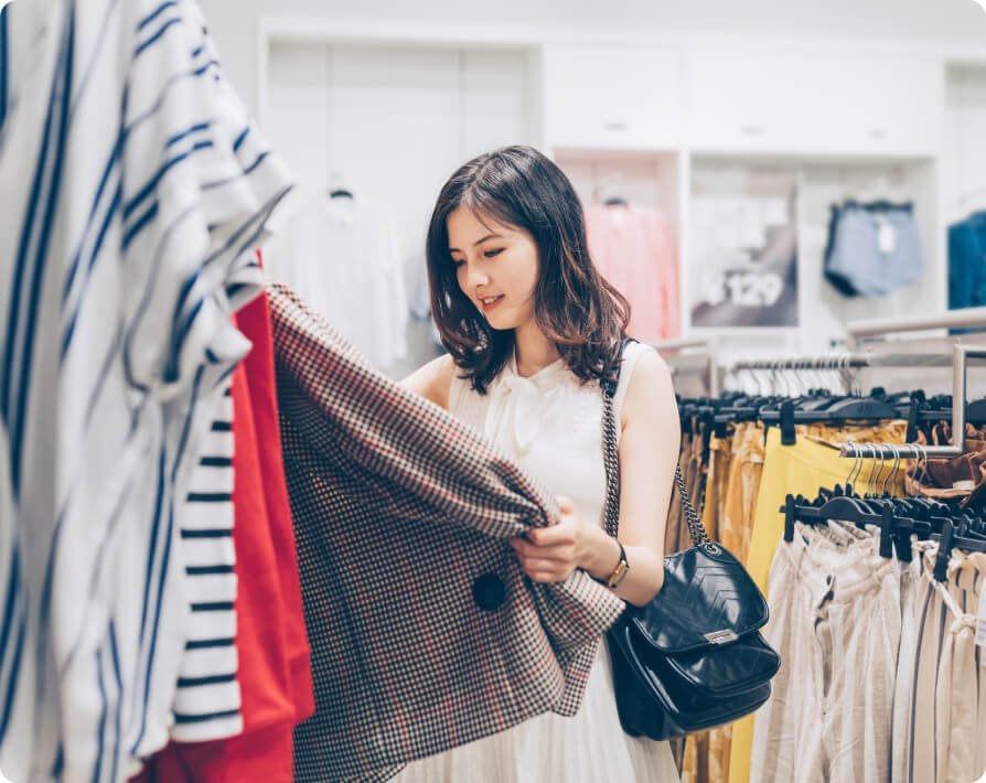 Una mujer sosteniendo un saco que está colgado en un rack dentro de una tienda.
