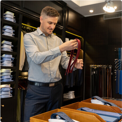 Un hombre dentro de una tienda de ropa sosteniendo una corbata.