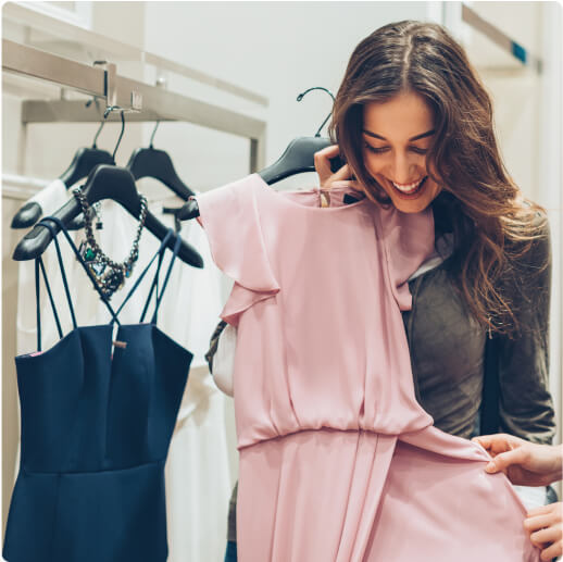 Una mujer dentro de una tienda sosteniendo un vestido frente a ella.