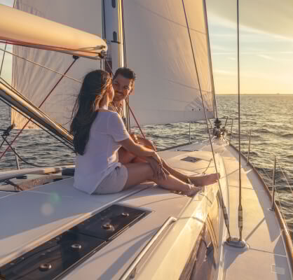Una pareja sentada en un velero contemplando el atardecer.
