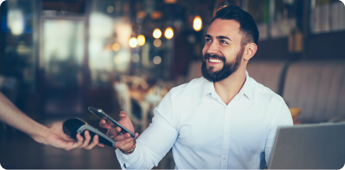 Una persona pagando con Apple Pay su cuenta en un restaurante.