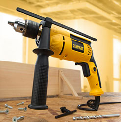 Rotomartillo para perforar concreto con broca y llave de mandril Dewalt amarillo y tornillos sobre mesa
