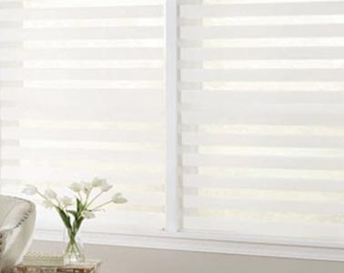 Persiana sheer elegance blanca en ventana iluminada junto a florero con tulipanes.